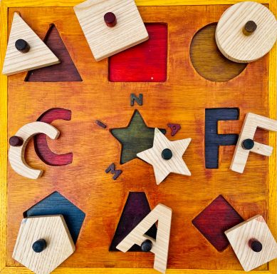 Wooden shape puzzle with various geometric shapes and a colourful base.