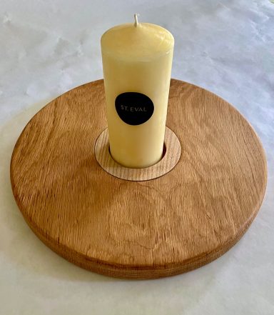 A round wooden candle holder with a yellow candle placed in the centre.