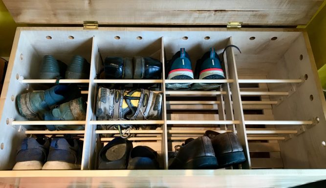 Wooden shoe storage box with various pairs of shoes neatly organised.