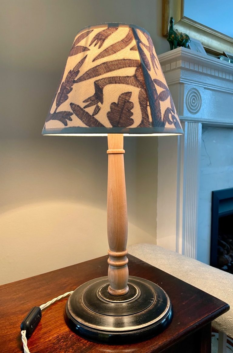 Table lamp with a floral patterned shade and a wooden base on a wooden surface.