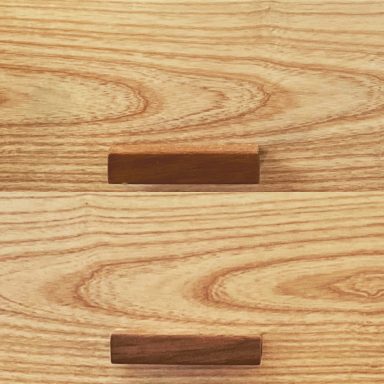 Two wooden drawers with simple, horizontal wooden handles on a light wood background.